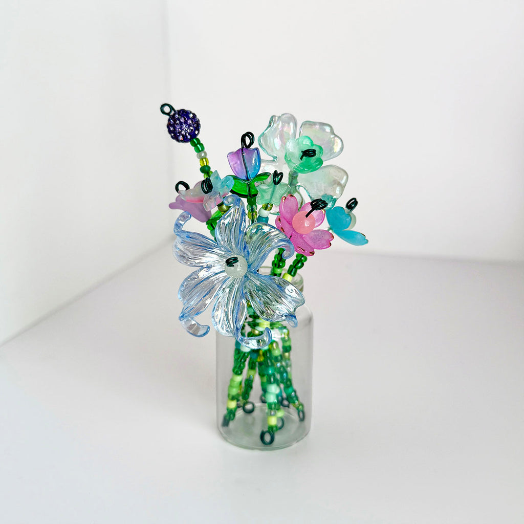 a glass jar with a variety of beaded flowers