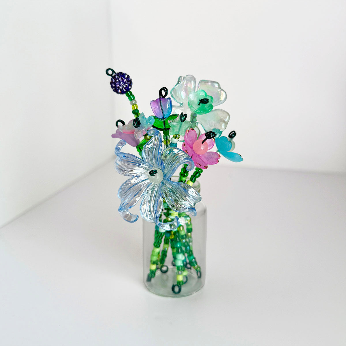 a glass jar with a variety of beaded flowers