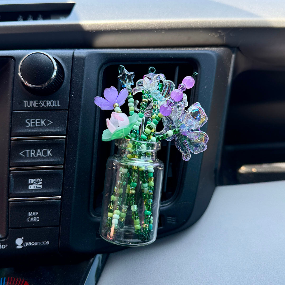 a glass jar with a variety of beaded flowers in a car