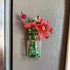 a glass jar with a variety of beaded flowers on a fridge