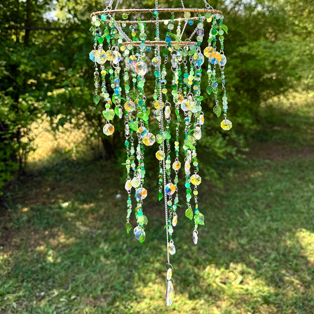 Decorative hanging crystal chime with green and clear beads against a natural background