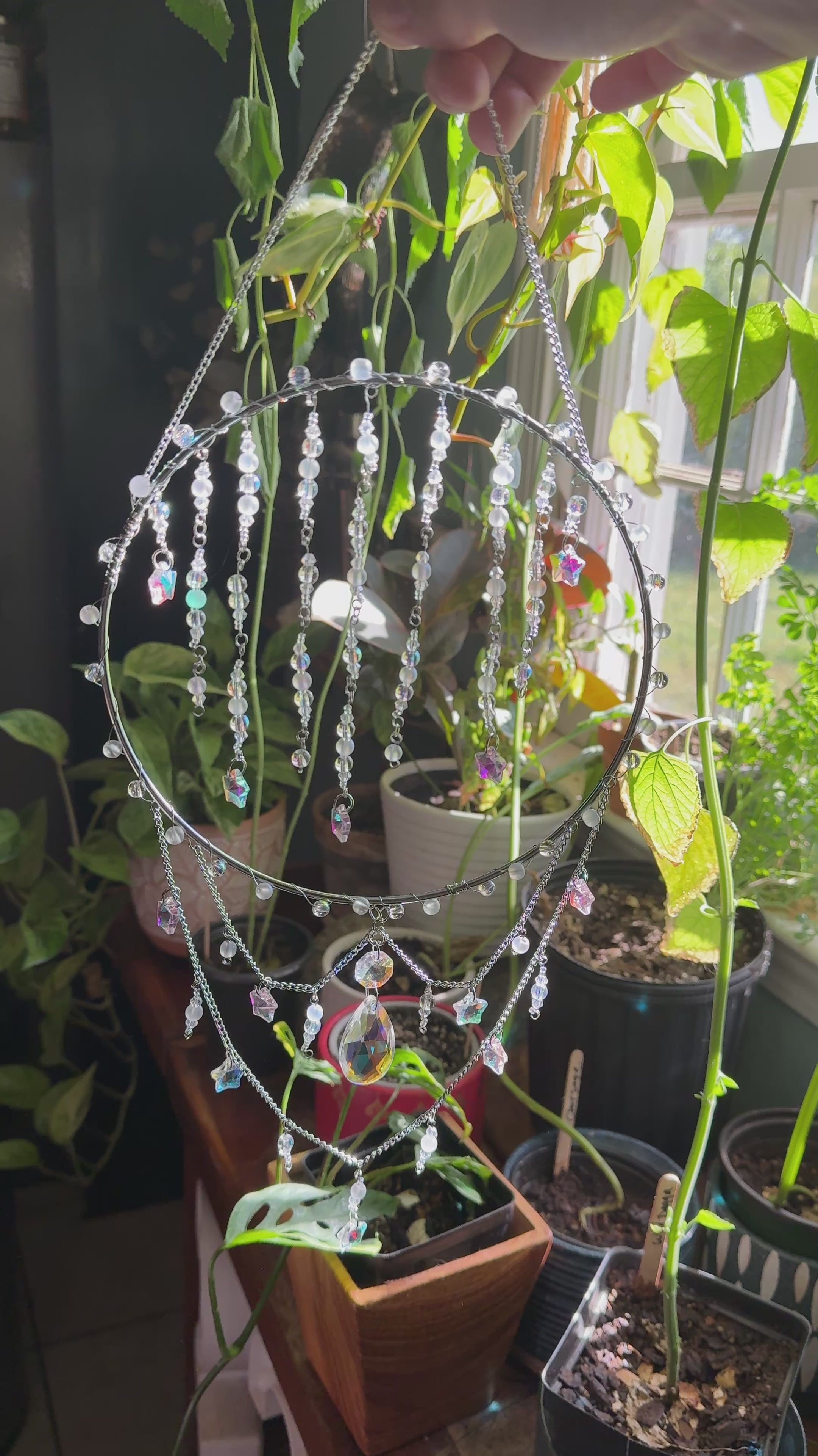 video of a circle suncatcher with clear beads and plants in the background